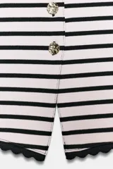 Top tipo chaleco sin mangas y con cuello redondo, con diseño de rayas horizontales, botones metálicos dorados en el frente y bordes con terminación en ondas.
