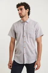 Camisa azul de manga corta, con cuello abotonado y bolsillo en el pecho.