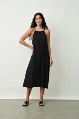 Vestido midi de color negro con escote halter y breteles finos. Presenta un corte holgado y fluido con caída suave.