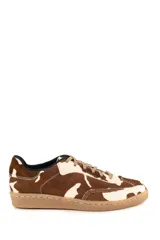 Championes de estilo urbano con diseño de manchas tipo vaca, confeccionados en cuero con textura de pelo. Presentan cordones al tono y suela de goma plana en color tostado.