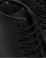 Botas de caña alta Dr. Martens modelo 1460, color negro, confeccionadas en cuero de plena flor con diseño de ocho ojales, cordones negros y suela gruesa con costuras amarillas características de la marca.