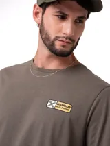 Remera verde militar de manga corta y cuello redondo, con pequeño parche estampado del logo de Caterpillar en el pecho.