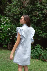 Vestido corto color verde oliva de lino con cuello mao fruncido, volados en los hombros, caída recta y botones al frente.