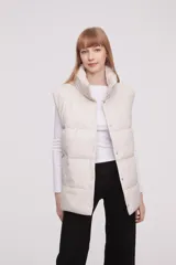 Chaleco acolchado color marfil con cuello alto y cierre frontal con botones a presión.