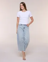 Jean de tiro medio y calce holgado con silueta curva y corte baggy, color azul claro. Cuenta con costuras diagonales estructuradas en el frente, cinco bolsillos, presillas en la cintura y cierre frontal con botón metálico. Presenta un ruedo al tobillo con acabado desflecado e irregular.