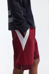 Short deportivo de nylon en bloques de color rojo, bordó y blanco. Cuenta con elástico revestido y cordón de ajuste blanco en la cintura, bolsillos laterales, aberturas cortas en el bajo y suspensor interior de malla.