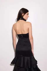 Top de tafeta color negro con escote halter y volados en el cuello, ajuste al cuerpo, espalda baja y cierre con botones.