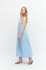 Maxi vestido celeste con rayas verticales blancas, cuello halter y lazo ajustable en la cintura.