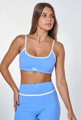 Conjunto deportivo compuesto por un top y un short de color celeste con detalles en blanco. El top tiene breteles finos y el logo 'bk.' estampado en el frente. El short es de tiro alto con una banda blanca horizontal en la cintura y líneas laterales blancas.