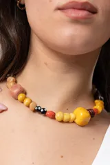 Gargantilla de cuentas artesanales multicolores en tonos amarillos, marrones y detalles en negro y blanco.
