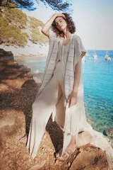 Chaleco largo de tejido de punto color azul verdoso, sin mangas y con flecos en el ruedo. Presenta calados con diseño geométrico.