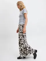 Pollera larga de corte recto confeccionada en tejido mesh con estampado animal print tipo vaca en tonos blanco y marrón oscuro. Presenta cintura elastizada y diseño fluido.