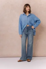 Pantalón de jean con tiro alto y corte wide leg, de color azul con efecto desgastado. Cuenta con cierre y botón frontal, además de bolsillos funcionales.