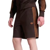 Bermuda Adidas modelo Firebird color marrón, con las clásicas tres tiras en los laterales en tono tostado, bolsillos con cierre y logo del trébol bordado.