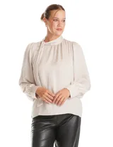 Blusa negra de acabado satinado con cuello alto fruncido, detalle de lazo para anudar y cierre lateral con botones. Presenta mangas largas estilo balloon con puños ajustados.