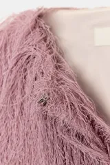 Chaqueta bomber de cuello redondo y manga larga, confeccionada con un acabado de flecos largos en toda la prenda. Presenta cierre frontal con corchetes y puños elásticos.