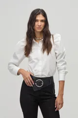Camisa blanca de popelina de algodón con cuello camisero clásico, hombros abullonados, mangas largas y botones de nácar en el frente.