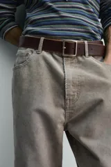 Pantalón de pana de corte flare, color verde oliva desgastado, con cinco bolsillos y cierre frontal de cremallera y botón.