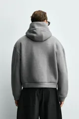 Sudadera tipo hoodie de corte boxy fit, confeccionada en tejido doble y compacto de mezcla de algodón. Presenta cuello con capucha, manga larga y acabados en el mismo tejido.