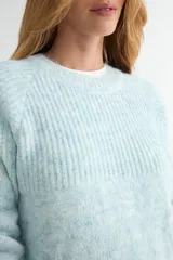 Buzo de tejido de punto con textura suave, color celeste pastel con efecto jaspeado. Presenta cuello redondo, mangas largas con terminación en puño y un diseño de canalé en la parte superior del pecho.