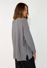 Sweater de punto color verde oliva, con cuello redondo, mangas largas y diseño holgado con costuras visibles en los laterales.