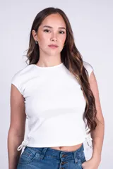 Remera entallada blanca de manga corta y cuello redondo, confeccionada en tejido rib con detalles de tiras ajustables fruncidas en los costados.