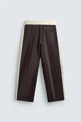 Pantalón jogger de corte wide fit en tejido compacto color gris oscuro. Presenta cintura elástica con cordón ajustable, bandas laterales en contraste color beige y costuras frontales tipo pinza.
