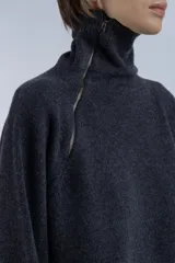 Sweater de lana superfina color gris, con corte holgado, mangas largas y cuello alto con medio cierre lateral.