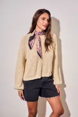 Sweater de tejido bouclé texturado color beige, con cuello redondo y mangas largas holgadas de corte amplio.