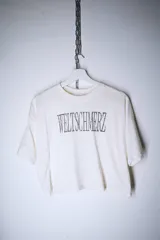 Remera blanca de corte holgado con estampa frontal en color negro que presenta la palabra Weltschmerz con un diseño tipográfico geométrico.