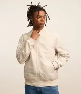 Campera bomber color beige, con cuello alto, cierre frontal con cremallera, bolsillos laterales y puños y cintura elastizados.