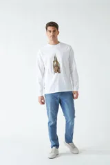 Remera blanca de manga larga con cuello redondo y estampado de un edificio antiguo.