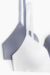 Pack de dos soutiens suaves de microfibra, uno blanco y otro gris azulado, con copas acolchadas sin aros, breteles ajustables y cierre de corchetes en la espalda.