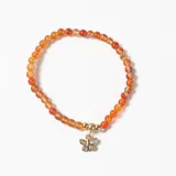 Pulsera elástica de cuentas de piedra natural en tonos anaranjados, con un dije central de mariposa dorada con incrustaciones de cristales.