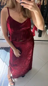 Falda midi de corte recto, confeccionada en tela satinada con textura arrugada en color bordó. Presenta un diseño elegante y fluido.