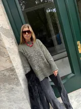 Buzo de tejido de punto grueso color marrón con diseño geométrico y floral estampado en color rojo. Presenta cuello redondo, mangas largas y puños y ruedo acanalados.