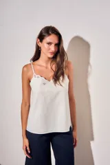 Musculosa blanca de viscosa con tirantes finos, escote en V y detalle de bordado floral con recortes en el borde superior.