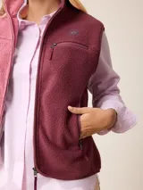 Chaleco de sherpa color beige con cierre frontal completo, cuello alto y bolsillo con cierre en el pecho que incluye un detalle circular con logo.