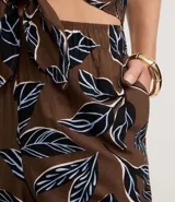 Pantalón tipo pantacourt de calce holgado y tiro alto, confeccionado en tejido de viscosa con estampa de follaje en tonos negro, blanco y azul sobre fondo marrón. Posee cintura elástica.
