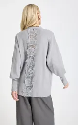 Cardigan de punto color gris, de corte holgado, con escote en V profundo, cierre frontal de botones, mangas largas con puños ajustados y bolsillos delanteros aplicados.