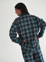 Pijama de franela a cuadros con estampado tartán, compuesto por una camisa de manga larga con solapas, bolsillo frontal y botones, y un pantalón largo de corte recto con puños y detalles en verde.