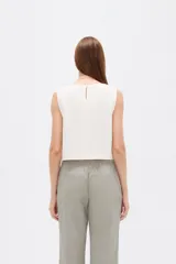 Musculosa sin mangas de color natural con cuello cuadrado y detalles de pliegues frontales en forma de chevrón.