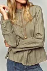 Camisa verde claro con cuello alto de puntilla, manga larga y detalles de entredoses calados en el pecho y los hombros. Cierre en la espalda con abertura y botón oculto.