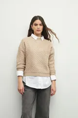 Sweater de punto con textura en relieve, cuello redondo y mangas largas con puños ajustados.