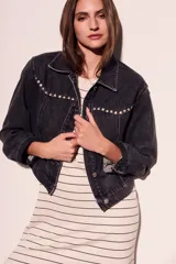 Campera de denim gris oscuro con tachas plateadas en cuello y solapas, corte cropped y mangas largas.