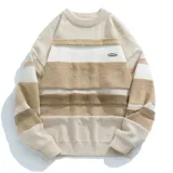 Buzo de tejido de punto con cuello redondo, manga larga y diseño de franjas horizontales en tonos beige, crema y marrón. Presenta textura en relieve en las franjas y un pequeño parche rectangular en el pecho.