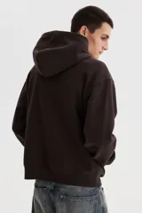 Campera canguro de felpa marrón oscuro, con cierre frontal completo, capucha, bolsillos delanteros tipo parche y pequeño bordado blanco en el pecho con texto y estrellas.