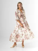 Vestido midi de estilo campesino confeccionado en organdí con estampa floral chintz de estilo romántico. Presenta escote en V cruzado, cintura completamente elastizada y falda larga con volados en niveles. Las mangas son tres cuartos con volados en los puños.