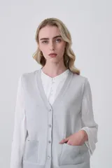 Chaleco de punto gris con escote en V, cierre frontal de botones y dos bolsillos delanteros con terminación acanalada.