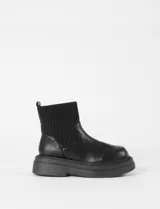 Botas tipo chunky de color negro, con caña de tejido elástico acanalado y base de goma gruesa dentada. Confeccionadas en cuero sintético.
